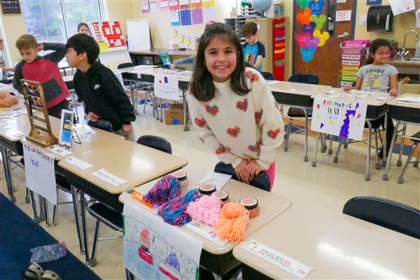 girl smiling with yarn on her desk